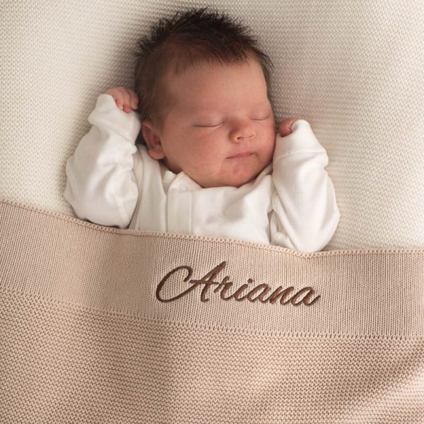 Newborn sleeping under Large Beige Knitted Blanket embroidered with girls name Ariana.
