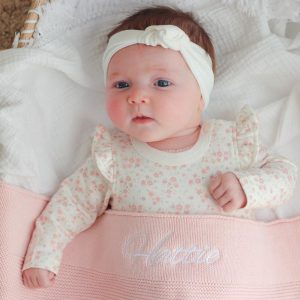 Pink knitted Blanket personalised with Hattie and covering a baby.