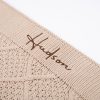 Close-up of beige diamond knit blanket edge with Hudson embroidered in brown thread