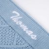 Close-up of personalised blue diamond knit baby blanket with white name embroidery on ribbed border