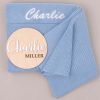 Blue Baby Blanket And Wooden Engraved Disc With Name Charlie Blue knitted baby blanket embroidered “Charlie” with wooden name disc reading “Charlie Miller.”