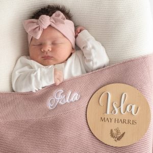 Personalised Blush Pink Blanket and 3D Baby Name Disc with girl laying underneath.