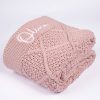 Blush Pink Diamond Knitted Baby Blanket Folded Blush pink cable knit personalised baby blanket rolled and folded showing diamond texture with white embroidered script name on white background.