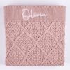 Blush Pink Diamond Knitted Baby Blanket Olivia Folded blush pink cable knit personalised baby blanket with white embroidered script name showing diamond pattern on white background.