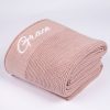 Blush Pink Knitted Baby Blanket Folded Blush pink knitted personalised baby blanket rolled and folded with white embroidered script name on white background.