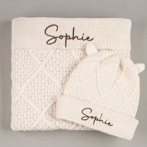 Cream diamond knit blanket and ear beanie with Sophie embroidered in brown on grey background
