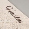 Cream Diamond Knitted Baby Blanket Close Up Close up of brown embroidered script name on cream cable knit personalised baby blanket showing stitch detail.