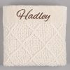 Cream Diamond Knitted Baby Blanket Hadley Folded cream cable knit personalised baby blanket with brown embroidered script name showing diamond pattern on grey background.