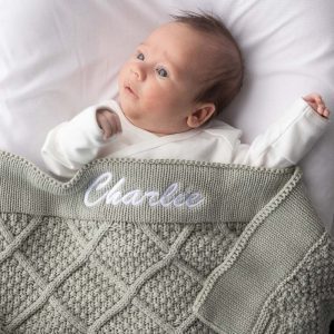 Newborn wrapped in personalised sage green diamond knitted baby blanket embroidered with the name Charlie.
