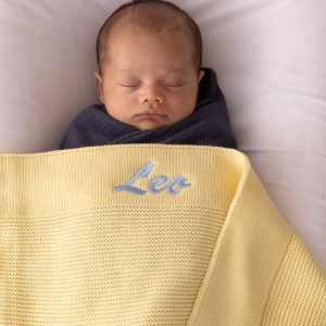 Personalised butter yellow knit baby blanket with tone on tone Leo embroidery on ribbed border.