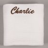 Personalised White Knitted Blanket Charlie Personalised white knitted baby blanket laid flat, showing "Charlie" embroidered in brown script along the top edge.
