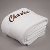 Personalised White Knitted Blanket Thick Personalised white knitted baby blanket folded neatly, embroidered with "Charlie" in brown script on one corner.