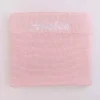 Folded personalised pink knit baby blanket with white embroidered name on ribbed border.