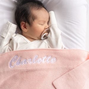 Baby Charlotte laying under a Pink Knitted Baby Blanket.