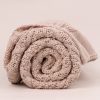 A Rolled beige diamond knitted baby blanket side on.