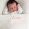 White Knitted Baby Blanket Sienna Lifestyle Baby laying under a white knitted cotton blanket personalised with the name Sienna with pink thread..