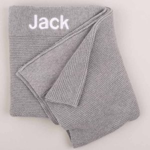 Grey Knitted Baby's Blanket embroidered in white with the name Jack with grey background.