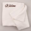 A white personalised baby blanket embroidered with the name Willow using brown thread.