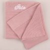 A blush pink knitted baby blanket embroidered with the girls name Isla.