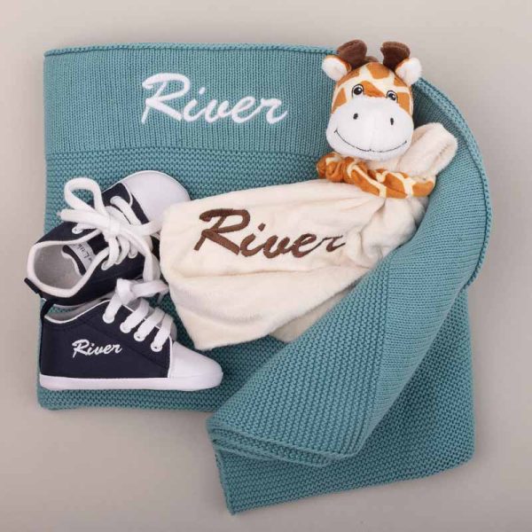 A baby gift set including knitted blanket, giraffe comforter and navy baby shoes.