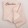 A personalised beige baby blanket embroidered with Charlie using brown thread.