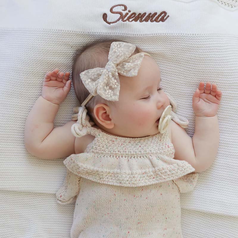 Baby Sienna laying on personalised white knitted blanket embroidered with her name