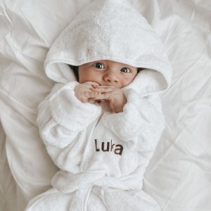 A baby in a personalised white hooded bath robe, first birthday present idea.