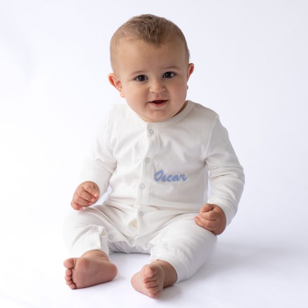 A Baby wearing a White Personlised Onesie embroidered with his name.
