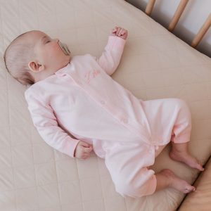 Baby wearing personalised pink onesie for girls embroidered with Zelie.