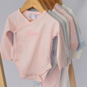 Personalised Baby Clothes with name embroidery hanging on hangers.