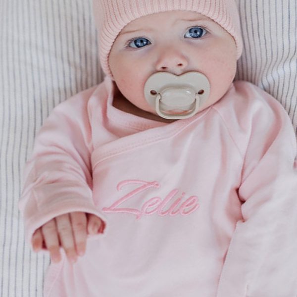 Baby girl wearing personalised pink romper Baby girl wearing personalised pink romper embroidered with Zelie newborn gift.
