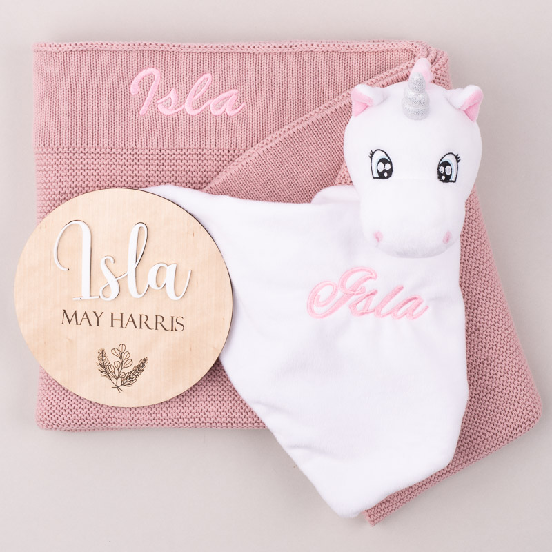 A Blush Pink knitted Blanket with a Unicorn comforter and a 3D Baby Name Disc personalised with the name Isla.