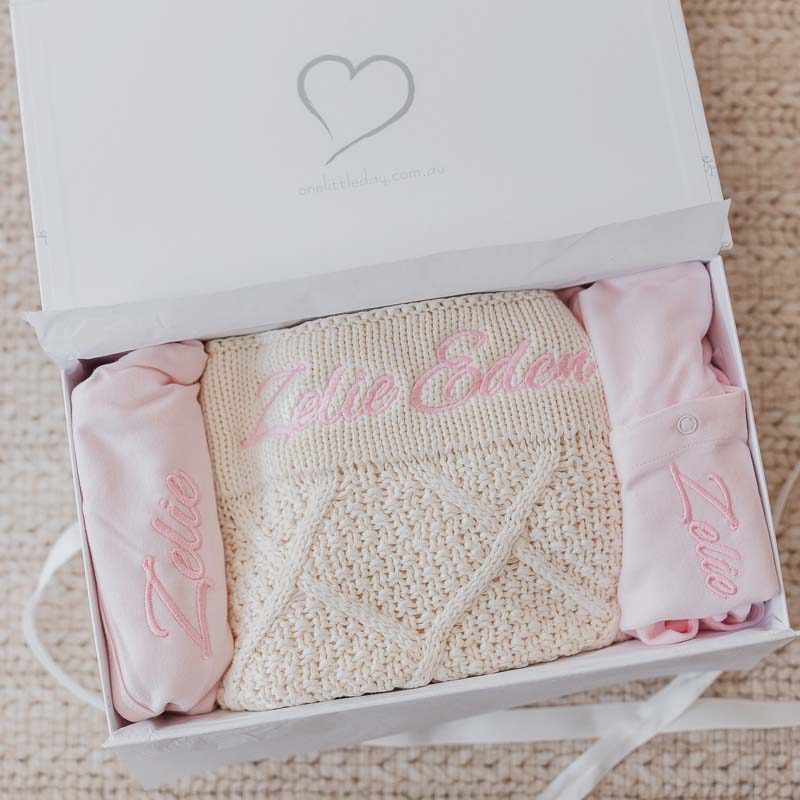 Personalised cream diamond baby blanket and pink baby girl clothes inside gift box.