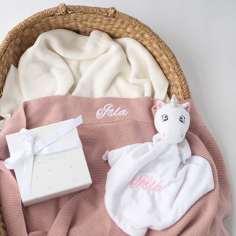Personalised unicorn baby comforter and blush pink knitted blanket newborn girl gift ideas in a basket.