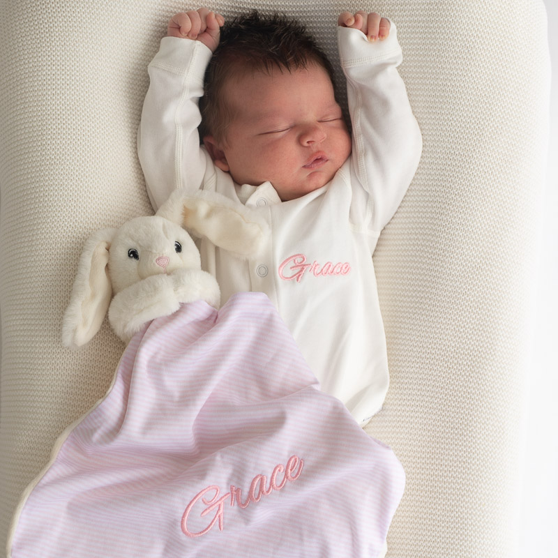 Baby wearing personalised white onesie with bunny comforter present ideas for newborn girls.