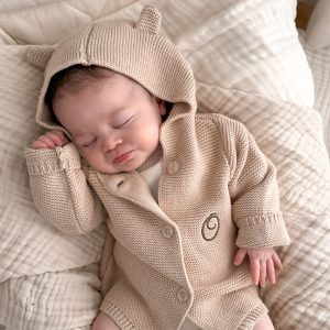 A baby wearing a Beige Hooded Knitted Baby Cardigan monogrammed with the letter O.