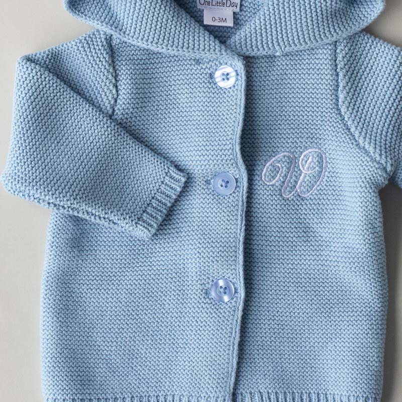 A close up of a Blue Hooded Cardigan and the letter W.