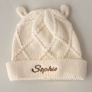 Cream knitted baby beanie with diamond pattern, bear ears, & personalised name embroidery on the fold.