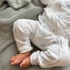 Koala Baby Zip Onesie Close Up Close-up of baby feet in white koala and eucalyptus print zip romper on sage knit blanket.