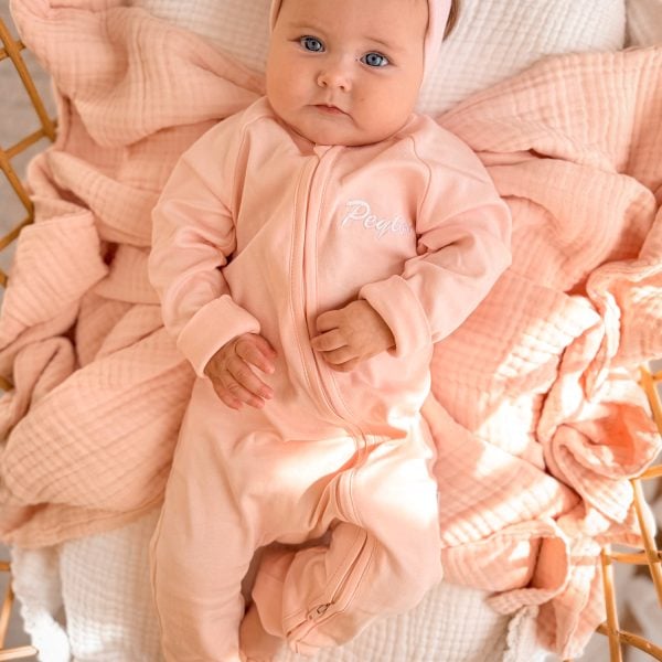 Personalised Pink Zip Baby Onesie Peyton Personalised pink zip footed onesie with Peyton embroidered in white on baby lying on muslin wrap