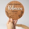 A hand holding a Creative 3D Birth Announcement Disc - Dark engraved with the name Rebecca.