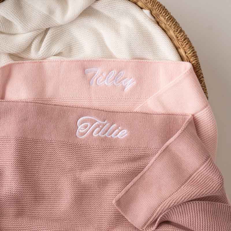 Two Pink Baby Girl Blankets personalised with baby name embroidery in a basket.