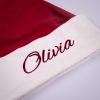 Burgundy Christmas Baby Hat Close Up Close up of white velvet baby Santa hat cuff with burgundy embroidered script name on burgundy velvet hat.
