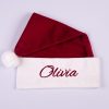 Burgundy Christmas Baby Hat Olivia Burgundy velvet personalised baby Santa hat with white cuff, pompom and burgundy embroidered script name on white background.