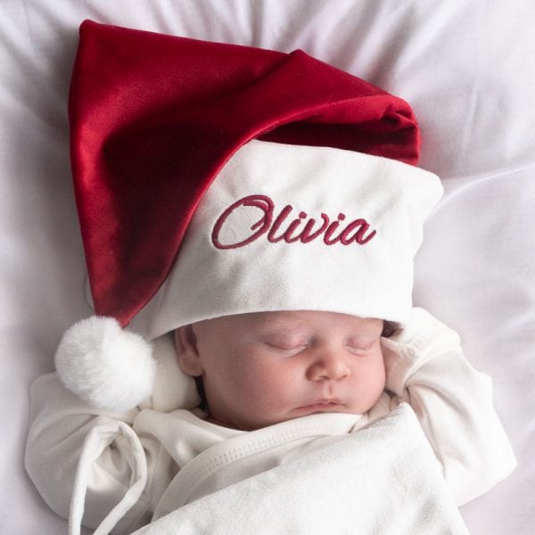 Burgundy Christmas Hat & Baby Sleeping baby wearing a personalised red and white Christmas hat embroidered with the name “Olivia.”
