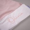 Light Pink Baby Christmas Hat Close Up Close up of white velvet baby Santa hat cuff with pink embroidered script name on light pink velvet hat.