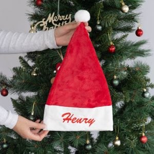 Personalised red faux fur Santa hat with white cuff and Henry embroidered in red with pom pom.