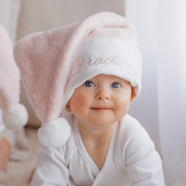 Pink Baby Christmas Hat Baby wearing personalised pink Christmas hat with name embroidery from One Little Day.
