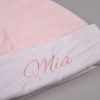 Pink Baby Christmas Hat Close Up Close up of white velvet baby Santa hat cuff with pink embroidered script name on pink faux fur hat.