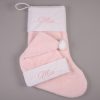 Pink faux fur personalised baby Christmas stocking and matching Santa hat with cream cuffs, pompom and pink embroidered script name on grey background.
